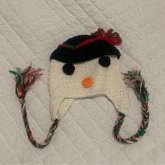 a crocheted snowman hat on top of a white quilted bed sheet