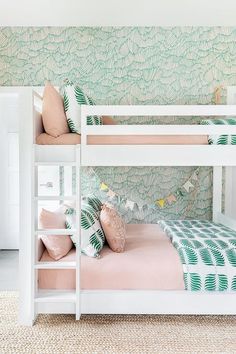 a white bunk bed with pink and green pillows