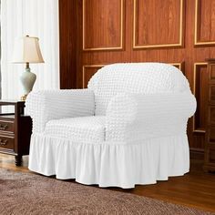 a white chair sitting on top of a wooden floor next to a lamp and dresser