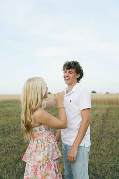 a young man and woman standing next to each other in a field