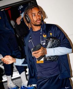 a man with dreadlocks and headphones holding a cell phone in his hand