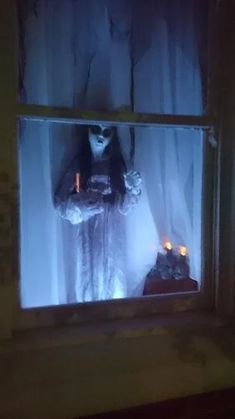 a creepy doll is standing in the window sill with candles on it's windowsill