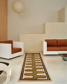 a living room with two couches and a rug on the floor in front of stairs