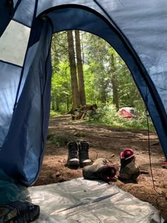 there is a tent in the woods with two boots on the ground next to it