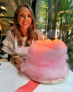 a woman sitting at a table with a pink cake