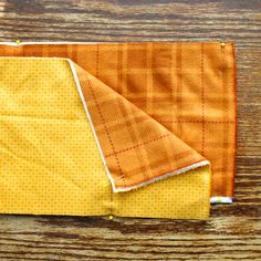 an orange and yellow piece of cloth sitting on top of a wooden table