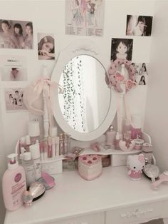 a white vanity topped with a mirror and lots of pink items on top of it