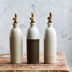 three white and brown bottles sitting on top of a wooden table