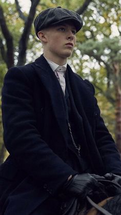 a young man riding on the back of a brown horse in a wooded area with trees