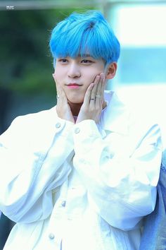 a young man with blue hair and piercings on his ears is posing for the camera