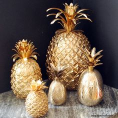 three gold pineapples sitting on top of a marble table