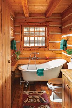 a bathroom with a tub, toilet and rug in the floor next to it's windows