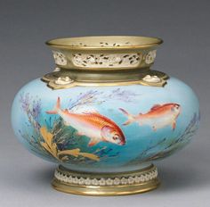 a vase with fish painted on it and gold trimmings around the bottom,