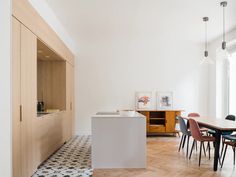 a dining room table with chairs and an island in the middle is surrounded by white walls