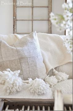 a white couch with some pillows on top of it and a window in the background