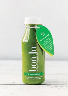 a bottle of green smoothie sitting on top of a wooden table