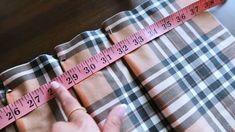 a woman measuring the length of her plaid skirt with a tape measure on top of it