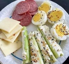 a white plate topped with meat, cheese and veggies next to crackers