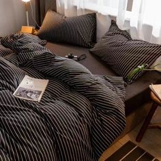 a bed with black and white striped comforter next to a lamp on a table