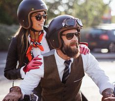 a man riding on the back of a motorcycle next to a woman wearing a helmet