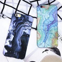 two phone cases sitting next to each other on top of a white table with black and blue designs