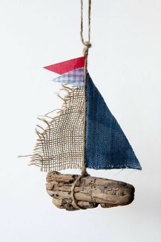 a sailboat hanging from a rope on a white wall next to a wooden shoe