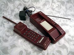 two old style phones sitting on top of a bed