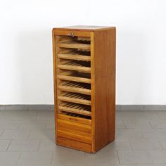 a wooden cabinet with many compartments on the front and bottom shelves, in an empty room