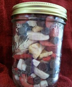 a jar filled with lots of different types of fruit and veggies on top of a red blanket