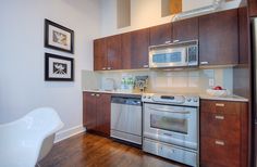 a modern kitchen with stainless steel appliances and wood flooring is pictured in this image