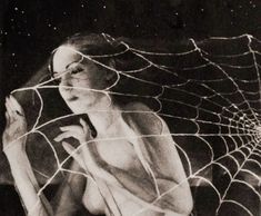 a woman is sitting in front of a spider web