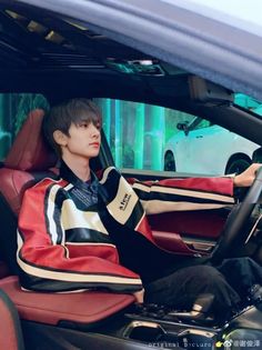 a young man sitting in the driver's seat of a car