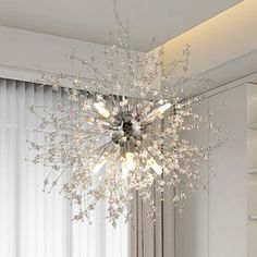 a chandelier hanging from the ceiling in a room with white walls and curtains