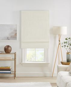 a living room filled with furniture and a large window covered in white roman blind shades