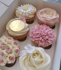 cupcakes in a white box with pink and white frosting flowers on them