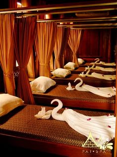 several beds with swans on them in a room that has curtains and drapes hanging from the ceiling