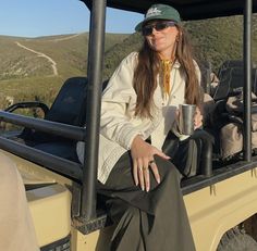 a woman sitting in the back of a truck holding a cup