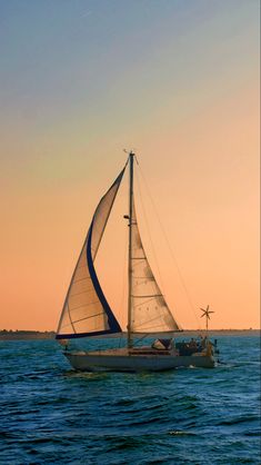 a sailboat sailing on the ocean at sunset