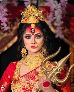 a woman dressed in red and gold holding a pair of scissors