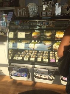 a person taking a photo of some pastries in a display case at a bakery