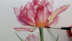 a person is painting a flower with watercolors