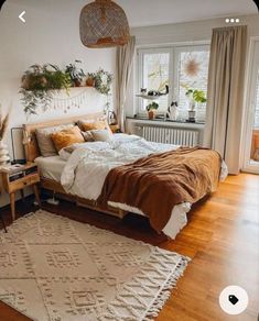 a bedroom with a bed, rug and plants in the window sill on the wall