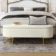 a white bed sitting on top of a wooden floor next to a night stand with two pillows