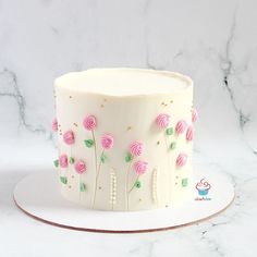 a white cake with pink and green frosting on a marble tablecloth covered plate