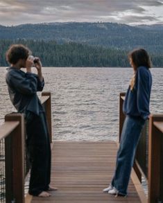 two people standing on a dock taking pictures