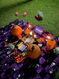 a table topped with lots of candy and pumpkins on top of a purple blanket