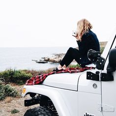 a woman sitting on top of a white jeep