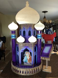 an elaborately decorated purple and gold building with lights on it's sides in a living room