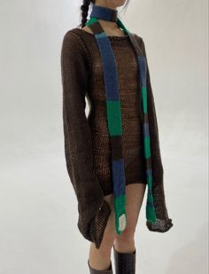 a woman is wearing a brown sweater with green, blue and black stripes on it