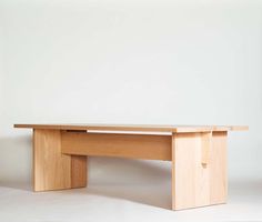 a wooden bench sitting on top of a white floor in front of a plain wall